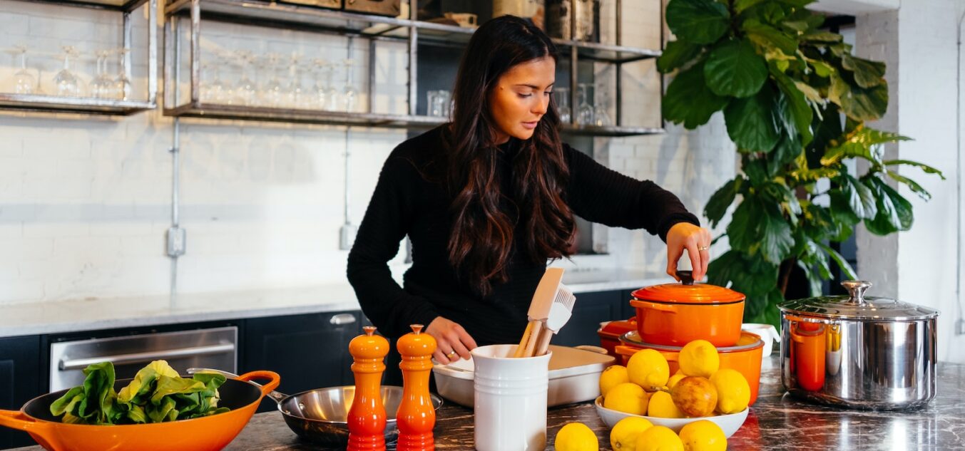 woman standing in front of fruits holding pot's lid