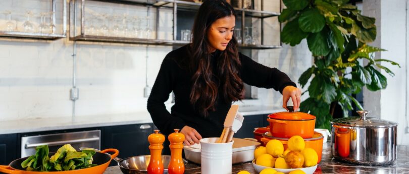 woman standing in front of fruits holding pot's lid